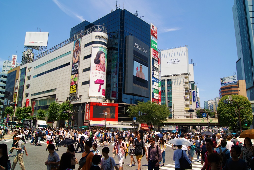 Busy traffic and pedestrians crossing at Shibuya crossing under summer sun